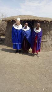 three people standing in front of a hut at SURUNGAI EMANYATA Maasai Boma in Arusha