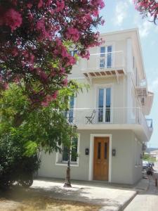ein weißes Haus mit einem Baum mit rosa Blüten in der Unterkunft Verani suites Lefkas Town in Lefkada Town