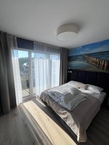 ein Schlafzimmer mit einem großen Bett und einem großen Fenster in der Unterkunft Apartamenty MIW Dziwnów 21 in Dziwnów