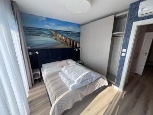 ein Schlafzimmer mit einem Bett mit einem Gemälde eines Piers in der Unterkunft Apartamenty MIW Dziwnów 21 in Dziwnów