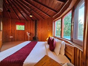 a bedroom with a large bed in a room with windows at The Vanya, Boutique Stay in Rāmgarh
