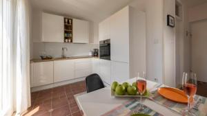 a kitchen with a table with a bowl of fruit and wine glasses at Vista Porto Apartment in Mali Lošinj