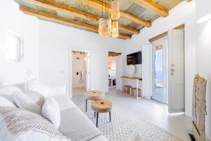 a white living room with a couch and two stools at Makarias Traditional Luxury Villas in Áno Meriá