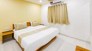 a bedroom with a large white bed and a window at Hotel Nova Safal in Rajkot