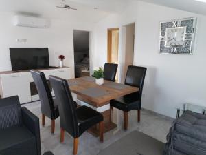 comedor con mesa de madera y sillas negras en Apartman Ivano, en Krnica