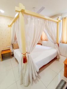 a bedroom with two beds with white curtains at Hotel Nova Safal in Rajkot