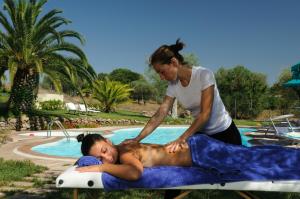 una mujer ayudando a un hombre tendido en una balsa junto a una piscina en Alghero Resort Country Hotel & Spa en Alghero