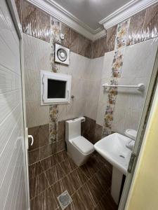 ein Bad mit einem WC und einem Waschbecken sowie einen TV in der Unterkunft الحى التجارى RED-13 ALhaddad in Salalah