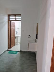 een badkamer met een wastafel, een spiegel en een deur bij Jade luxury apartments Diani in Mombasa