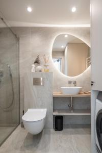 een badkamer met een toilet, een wastafel en een spiegel bij LightSummerPalanga in Palanga