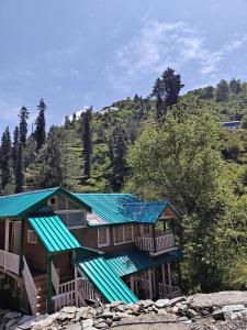 a house with green roofs on a mountain at La Vilasa in Jibhi