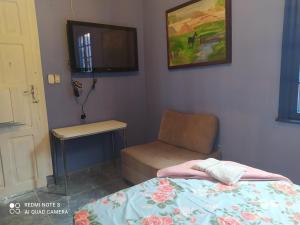 een slaapkamer met een bed, een stoel en een televisie bij Ufuk Hotel in Sao Paulo