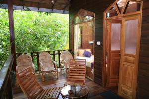 a porch of a cabin with chairs and a table at River Face Inn in Tissamaharama