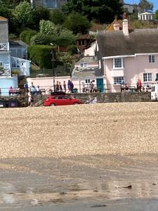 ein rotes Auto, das am Strand neben Häusern geparkt ist in der Unterkunft Dolphin Cottage Lyme Regis in Lyme Regis