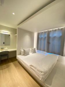 Matini Hostel grandstation في Bang Su: سرير أبيض في غرفة بها نافذة