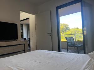 a bedroom with a bed and a television and a balcony at T2 Porticcio neuf in Porticcio +1 photo