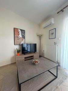 a living room with a tv and a coffee table at Theros Kalamitsa Apartment in Kavála +2 photos