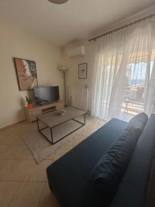 a living room with a couch and a tv at Theros Kalamitsa Apartment in Kavála