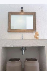 un bagno con uno specchio sopra un lavandino e due servizi igienici di Olea Apartments & Multidisciplinary Space a Piedras Blancas