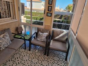 a balcony with two chairs and a table and windows at Casa La Florida in Orihuela