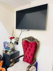 einem roten Stuhl neben einer Wand mit einem TV in der Unterkunft Serene Nest in Umm al-Qaiwain