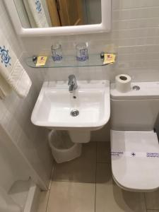 ein Badezimmer mit einem weißen Waschbecken und einem WC in der Unterkunft Hotel Maritimo in Alicante