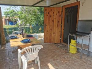 a patio with a wooden table and a grill at Small Robinson House 250m to the sea in Peroj +24 photos