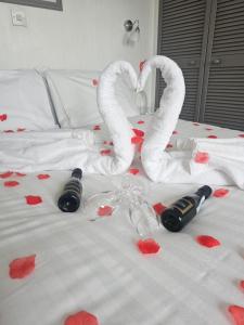 The Wight Bay Hotel - Isle of Wight في سانداون: سرير بقلوب حمراء وزجاجتين من النبيذ ومناشف