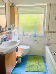 ein Badezimmer mit Waschbecken und Toilette und einem Fenster in der Unterkunft Nice and cozy House in Frisange