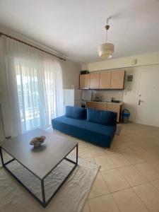a living room with a blue couch and a table at Theros Kalamitsa Apartment in Kavála