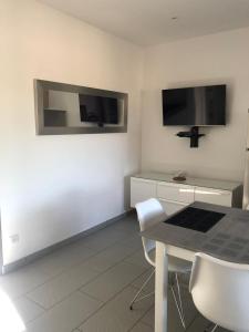 ein Esszimmer mit einem Tisch und einem TV an der Wand in der Unterkunft MINI VILLA entre mer et montagne PALAVESA in Porto-Vecchio