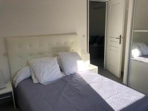 ein Schlafzimmer mit einem Bett mit weißen Laken und Kissen in der Unterkunft MINI VILLA entre mer et montagne PALAVESA in Porto-Vecchio