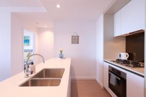 una cucina bianca con lavello e fornello di 09D 2Bedroom Abnb-Style Ocean view Apt with Free parking a Melbourne