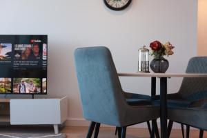 un tavolo da pranzo con due sedie blu e una TV di 09D 2Bedroom Abnb-Style Ocean view Apt with Free parking a Melbourne