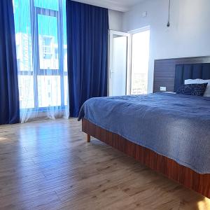 a bedroom with a bed with blue sheets and blue curtains at Seaside 2-Room 3-Balconies Apt#12 Stunning View in Batumi +15 photos