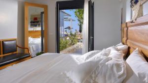 Una cama blanca con vista a un balcón. en Casa Blue Villa in Crete, en Agia Pelagia