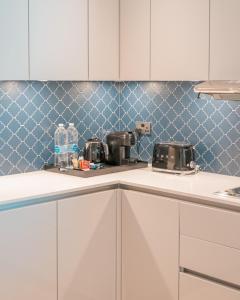 a kitchen with white cabinets and blue tiles at Abesq Doha Hotel and Residences in Doha