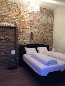 a bedroom with two beds and a brick wall at Het Kapelhuis in Thorn
