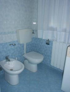 La salle de bains bleue est pourvue de toilettes et d'un lavabo. dans l'établissement Villa Cortina, à Rosolina Mare