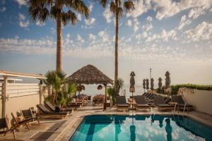 a pool at a resort with chairs and palm trees at Soleil Rooms and Suites in Stalís