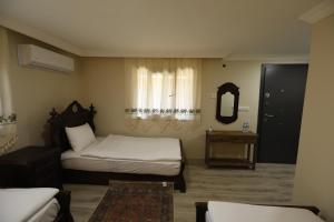 a bedroom with two beds and a mirror and a window at Nu-se Garden Butik Otel in Selcuk