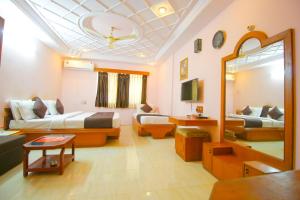 a living room with two beds and a mirror at Hotel Upasana in Rajkot