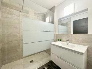 a white bathroom with a sink and a mirror at L'Opale - Vue mer in Calais +17 photos
