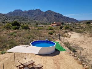 a swimming pool with an umbrella and some mountains at La bocana del Portús in Cartagena