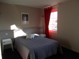 a bedroom with a bed with a blue blanket and a window at Hôtel Restaurant La Belle Epoque in Le Creusot