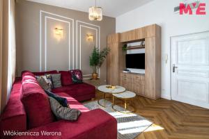 a living room with a red couch and a table at MYE Apartments - Verona Włókiennicza in Łódź