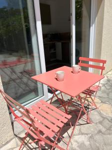 a red table and chairs with two cups on it at Studio avec terrasse privative in Pessac