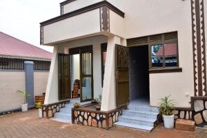 a house with a porch and stairs in front of it at Habermotel Enterprise Ltd in Entebbe