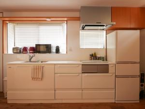 a kitchen with white cabinets and a sink and a window at Akizuki Meganebashi Cottage in Asakura