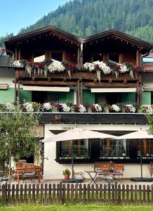 - un bâtiment avec des fleurs sur les balcons avec des tables et des chaises dans l'établissement Das Halali - dein kleines Hotel an der Zugspitze, à Ehrwald
